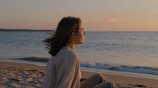 Mujer contemplando el mar al atardecer, transmitiendo calma y bienestar